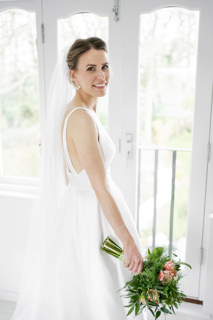 Bride standing by a window looking back at the camera